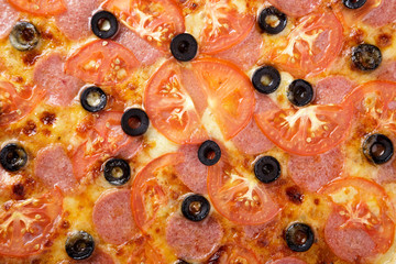 Delicious pizza. Large meat pizza with bacon, sausage, salami, pepperoni and olives. Homemade delicious italian pizza on wooden table for dinner. Italian cuisine.