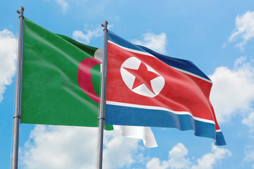 North Korea and Algeria flags waving in the wind against white cloudy blue sky together. Diplomacy concept, international relations.