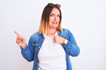Beautiful woman wearing denim shirt standing over isolated white background Pointing aside worried...