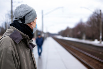 Fototapeta premium the guy in the respirator is waiting for the train. Concept: colds, flu, coronavirus