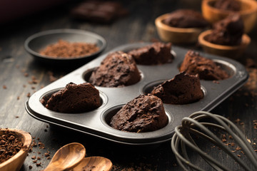 Cupcakes, muffins in a baking pan on a black table. Cupcakes, muffins on a wooden board and a black wooden table. Fresh French Baked Cupcakes. Warm Fresh Buttery Rolls