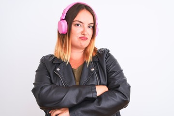 Young beautiful woman listening to music using headphones over isolated white background skeptic...