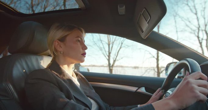 Caucasian good looking young woman in business style driving a car, being nervous, talking to herself and pushing the signal button.