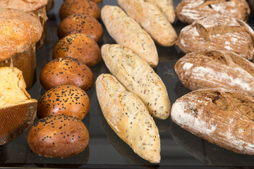 Different kinds of fresh bread on a table. Assortment of fresh bakery products on wooden table.
