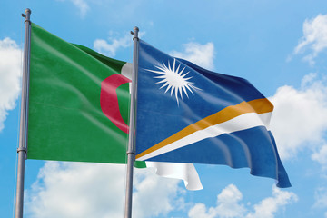 Marshall Islands and Algeria flags waving in the wind against white cloudy blue sky together. Diplomacy concept, international relations.