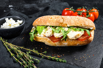 Ciabatta sandwich with fresh goat cheese, pear marmalade and arugula. Black background. Top view - obrazy, fototapety, plakaty