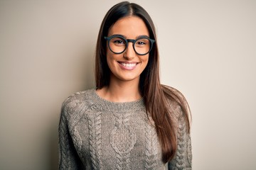 Young beautiful brunette woman wearing casual sweater and glasses over white background with a...