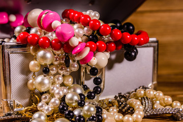 Aluminium case full of different jewelry on wooden table