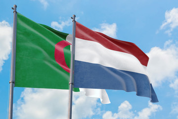 Netherlands and Algeria flags waving in the wind against white cloudy blue sky together. Diplomacy concept, international relations.