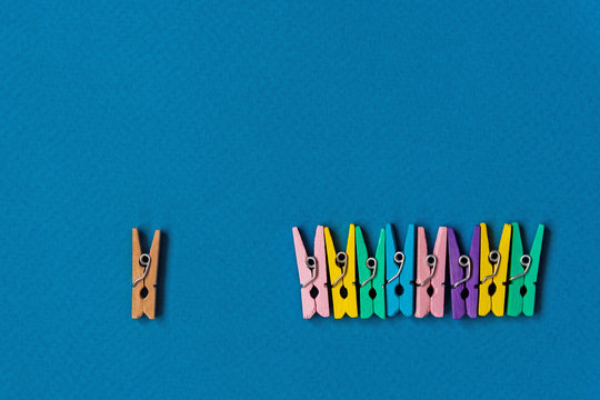 Think differently concept for group of colorful clothespins with another one colorless simple clothespin is stand alone.
