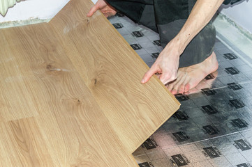 Fototapeta na wymiar Worker installing new wooden laminate flooring.