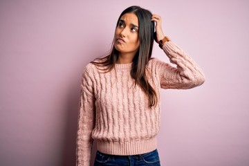Young beautiful brunette woman wearing casual sweater over isolated pink background confuse and...