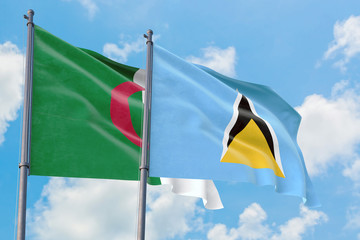 Saint Lucia and Algeria flags waving in the wind against white cloudy blue sky together. Diplomacy concept, international relations.