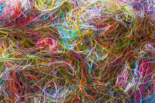 Multi-colored tangled threads abstract texture pattern background. Macro shot of colorful needlecraft silk thread ropes. Colored natural thread pile for sewing clothe scattered randomly like spaghetti