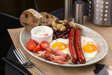 Homemade delicious american breakfast with sunny side up fried egg, toast, sausage, fruits, vegetable, strawberry jam, croissant