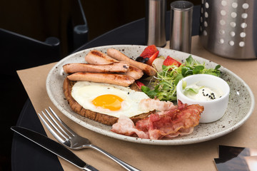 Homemade delicious american breakfast with sunny side up fried egg, toast, sausage, fruits, vegetable, strawberry jam, croissant