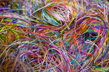 Multi-colored tangled threads abstract texture pattern background. Macro shot of colorful needlecraft silk thread ropes. Colored natural thread pile for sewing clothe scattered randomly like spaghetti