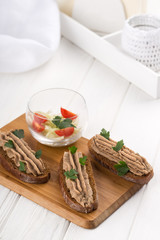 Bruschetta with pate on a white table. Bruschetta with liver pate and herbs on white table. Canape mini sandwiches