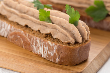 Bruschetta with pate on a white table. Bruschetta with liver pate and herbs on white table. Canape mini sandwiches