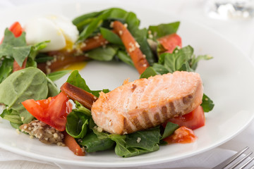 Salmon steak with vegetables on a white table. Grilled salmon steak with lemon and vegetables. Fish meal with fresh vegetable. Space for text
