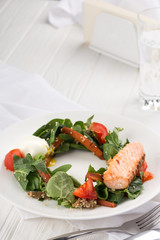 Salmon steak with vegetables on a white table. Grilled salmon steak with lemon and vegetables. Fish meal with fresh vegetable. Space for text