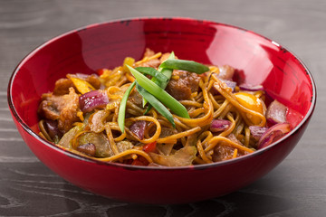 Stir fry with soba noodles, beef (meat) and vegetables. Udon. Asian healthy food, stir fried meal in bowls. Spicy noodles. Indo-chinese cuisine hot dish with udon noodles, vegetables and chilli sauce.