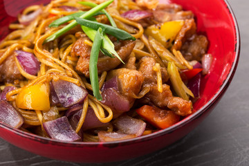 Stir fry with soba noodles, beef (meat) and vegetables. Udon. Asian healthy food, stir fried meal in bowls. Spicy noodles. Indo-chinese cuisine hot dish with udon noodles, vegetables and chilli sauce.