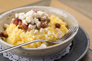 Banosh on a white table. Banosh with cheese and lard. Ukrainian cuisine. Typical Ukrainian dish polenta - Banosh with cheese, lard. Corn porridge with bacon, cracklings and cheese.