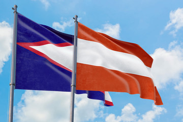 Austria and American Samoa flags waving in the wind against white cloudy blue sky together. Diplomacy concept, international relations.