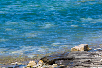 pebble stones on the sea beach, the rolling waves of the sea with foam