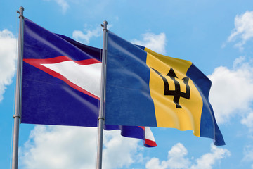 Barbados and American Samoa flags waving in the wind against white cloudy blue sky together....