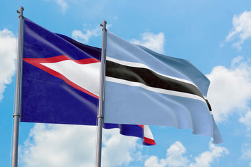 Botswana and American Samoa flags waving in the wind against white cloudy blue sky together. Diplomacy concept, international relations.