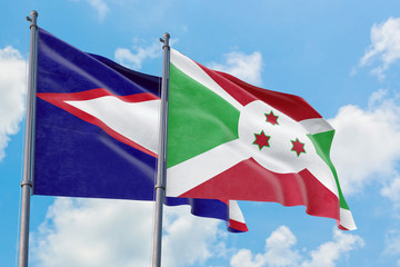 Burundi and American Samoa flags waving in the wind against white cloudy blue sky together. Diplomacy concept, international relations.