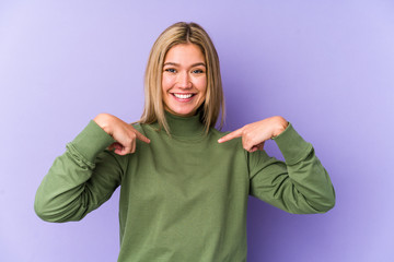 Young blonde caucasian woman isolated surprised pointing with finger, smiling broadly.