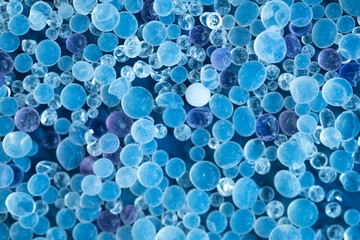 Close up - Pile of silica gel on blue background, Desiccant used in industrial, moisture protection. Desiccant Silica Gel (Moisture Absorber) Background. Blue and White Translucent Crystals Texture