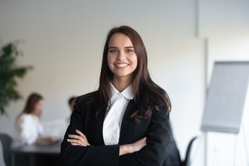 Headshot portrait businesswoman posing with arms crossed indoors
