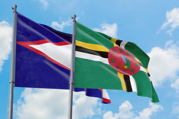 Dominica and American Samoa flags waving in the wind against white cloudy blue sky together....