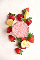 Delicious strawberry banana smoothie in a glass with ingredients for making. Top view with copy space.