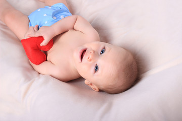 Cute baby with red toy heart in a blue diaper. Mother's day card concept