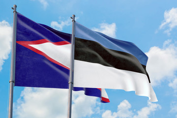 Estonia and American Samoa flags waving in the wind against white cloudy blue sky together. Diplomacy concept, international relations.