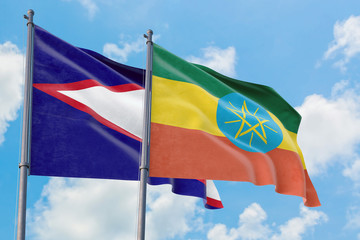 Ethiopia and American Samoa flags waving in the wind against white cloudy blue sky together....