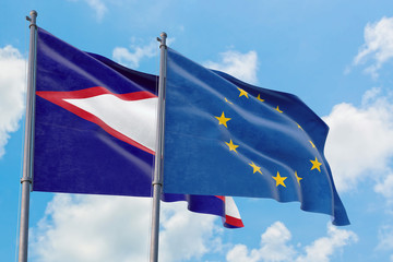 European Union and American Samoa flags waving in the wind against white cloudy blue sky together. Diplomacy concept, international relations.