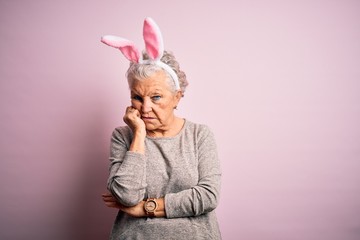 Senior beautiful woman wearing bunny ears standing over isolated pink background thinking looking...