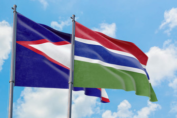 Gambia and American Samoa flags waving in the wind against white cloudy blue sky together. Diplomacy concept, international relations.
