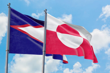 Greenland and American Samoa flags waving in the wind against white cloudy blue sky together. Diplomacy concept, international relations.