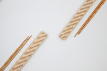 Bamboo mat with chopsticks for sushi on the white table.