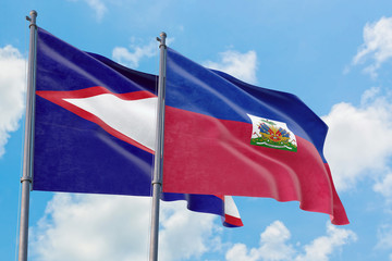 Haiti and American Samoa flags waving in the wind against white cloudy blue sky together. Diplomacy concept, international relations.