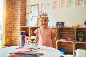 Beautiful blond toddler girl wearing princess crown standing at kindergarten