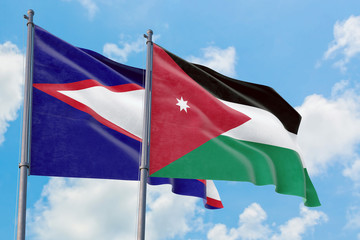 Jordan and American Samoa flags waving in the wind against white cloudy blue sky together....