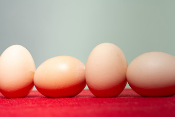 Whole eggs with set in a row on red background.